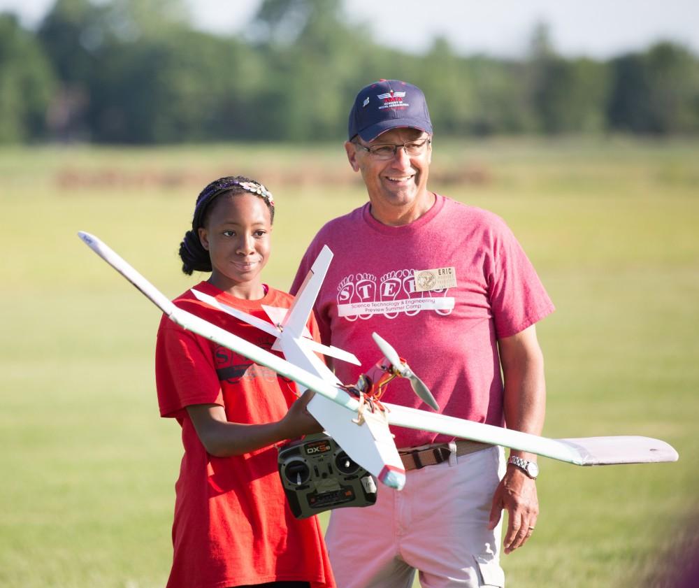 GVL / Kevin Sielaff - Koungo Diarrassouba holds up her plane and poses for a photo with her instructor. Students of STEPS (Science, Technology, and Engineering Day Camps) fly planes that they have built during camp at Warped Wings Fly Field in Allendale on Thursday, June 23, 2016. 