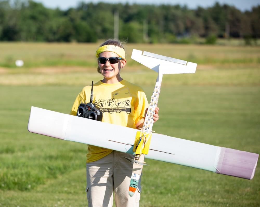 GVL / Kevin Sielaff - Alison Doerr holds up her plane after it has landed. Students of STEPS (Science, Technology, and Engineering Day Camps) fly planes that they have built during camp at Warped Wings Fly Field in Allendale on Thursday, June 23, 2016. 