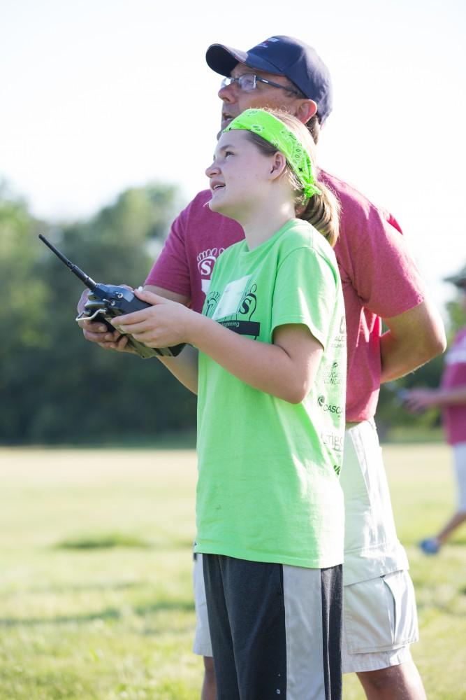 GVL / Kevin Sielaff - Aspen Postma flies her plane with the help of an instructor. Students of STEPS (Science, Technology, and Engineering Day Camps) fly planes that they have built during camp at Warped Wings Fly Field in Allendale on Thursday, June 23, 2016. 