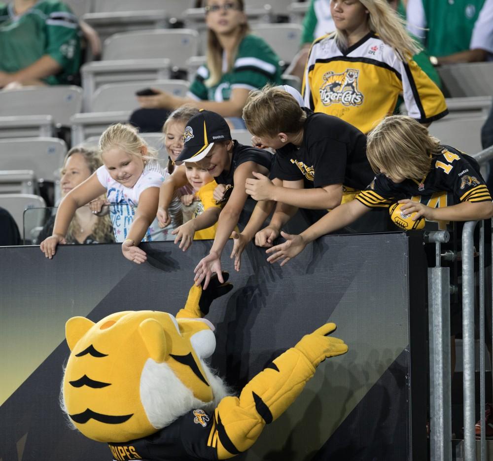 GVL/Kevin Sielaff - Children line up on the edge of the stands to high-five the Tiger-Cats mascot. The Hamilton Tiger-Cats square off against the Saskatchewan Roughriders Saturday, August 20, 2016 in Hamilton, Ontario. 