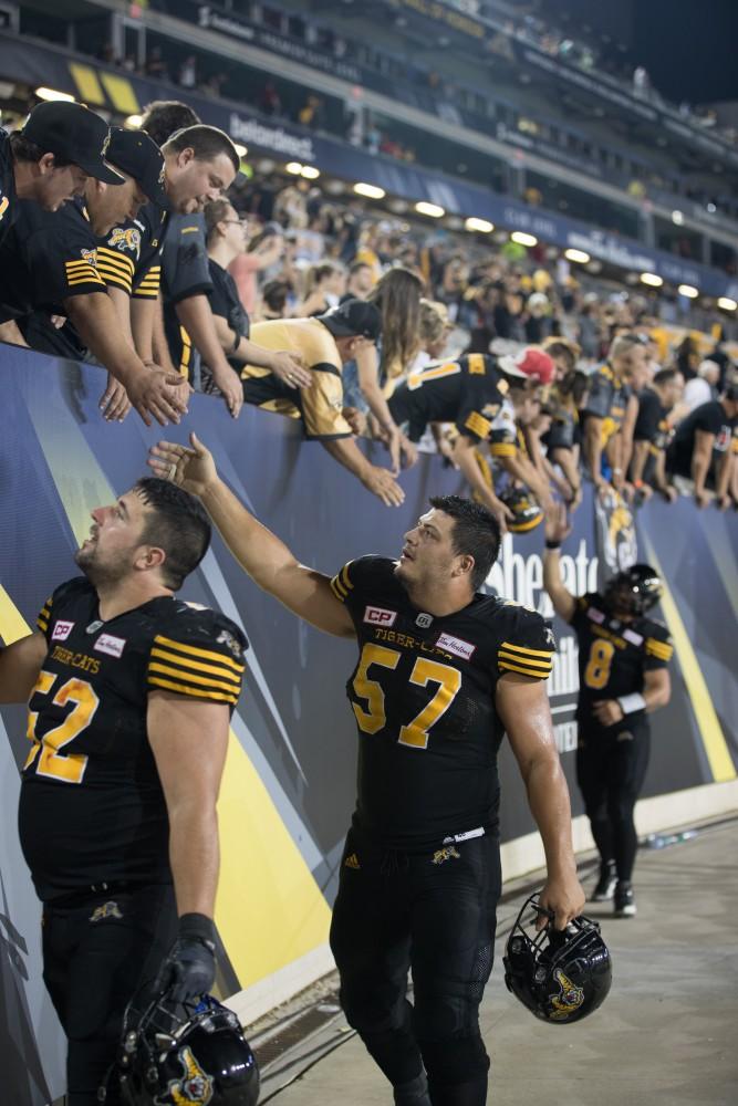 GVL/Kevin Sielaff - Brandon Revenberg (57) high-fives fans after the match. The Hamilton Tiger-Cats square off against the Saskatchewan Roughriders Saturday, August 20, 2016 in Hamilton, Ontario. 