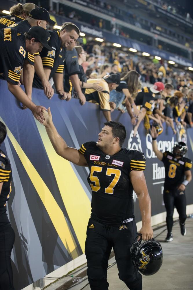 GVL/Kevin Sielaff - Brandon Revenberg (57) high-fives fans after the match. The Hamilton Tiger-Cats square off against the Saskatchewan Roughriders Saturday, August 20, 2016 in Hamilton, Ontario. 