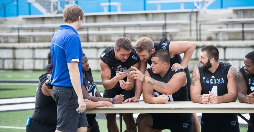 GVL / Kevin Sielaff - Seniors crowd around a phone as they plan their senior photo. Grand Valley State football hosts its annual media day at Lubbers Stadium on Thursday, August 25, 2016. 