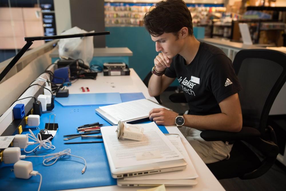 GVL / Luke Holmes - Dylan Kernohan reviews some paperwork at the Genius Phone Repair shop in the GVSU Marketplace.