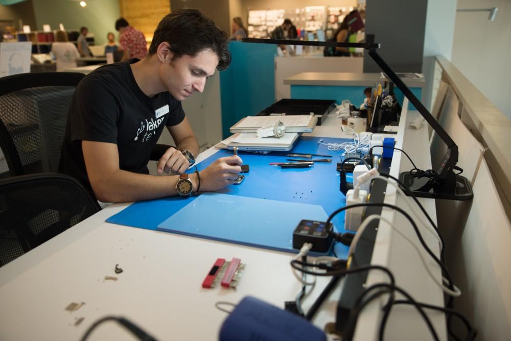 GVL / Luke Holmes - Dylan Kernohan works on a broken iPhone at the Genius Phone Repair shop in the GVSU Marketplace.
