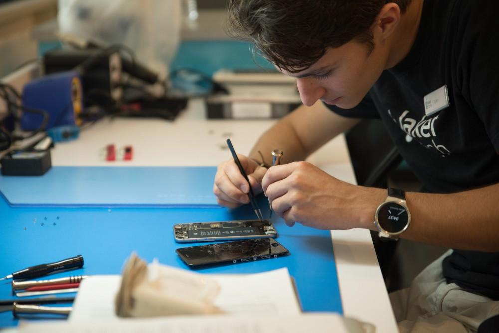 GVL / Luke Holmes - Dylan Kernohan works on a broken iPhone at the Genius Phone Repair shop in the GVSU Marketplace.