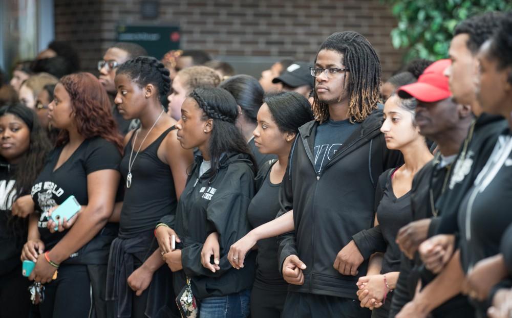 GVL/Kevin Sielaff - Marques Hill joins arms with those around him and participates in the end of the silent march within the Kirkhof Center. Grand Valley's NAACP chapter holds a campus wide demonstration in protest of police brutality Friday, Sept. 23, 2016 in Allendale.