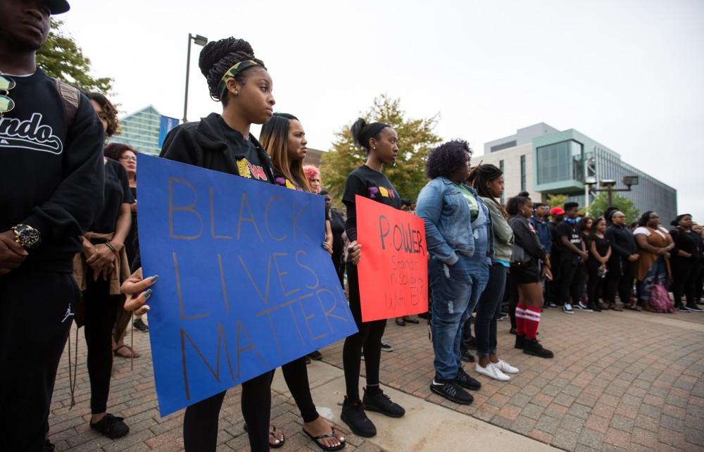 GVL/Kevin Sielaff - Cariese Cooks holds a Black Lives Matter sign as protestors gather around the clock tower. Grand Valley's NAACP chapter holds a campus wide demonstration in protest of police brutality Friday, Sept. 23, 2016 in Allendale.