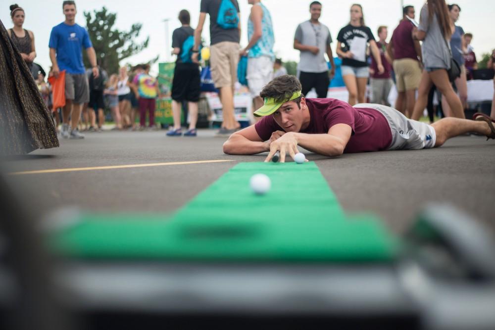 GVL / Luke Holmes - Alex Weitzel stops by the Golf Club table to try and sink a putt. Campus Night Life was held in the Parking Lot H on Tuesday, Sep. 6, 2016.