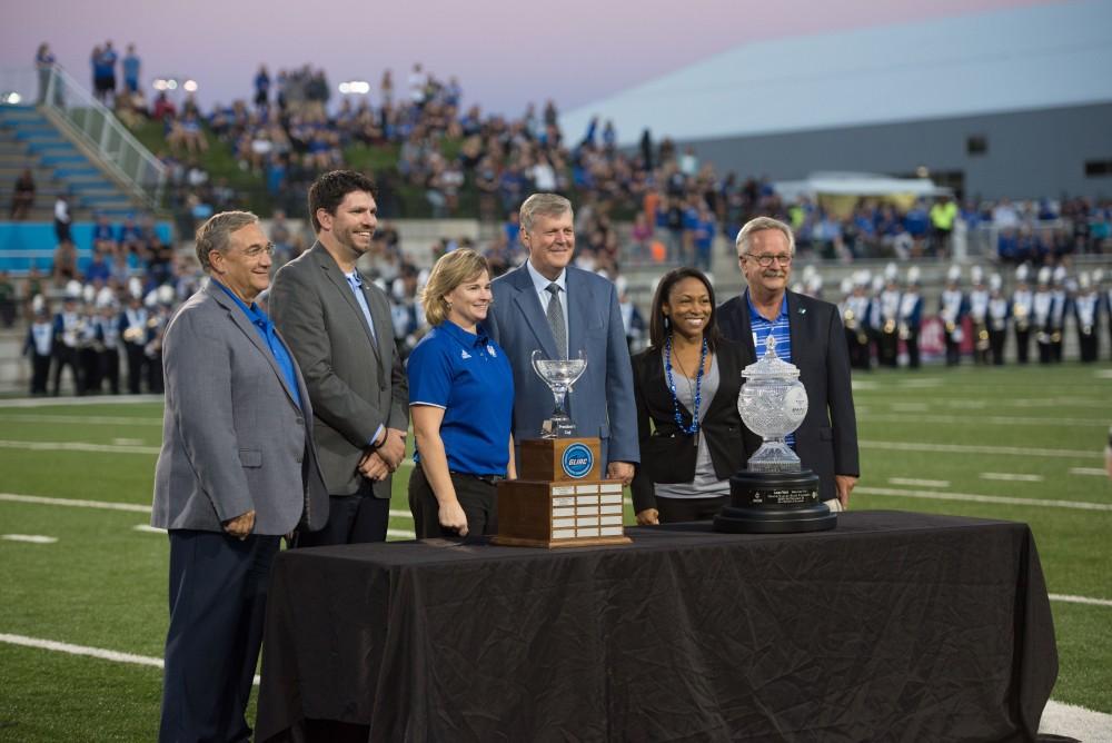 GVL / Luke Holmes - President Haas poses next to the President’s Cup at half time. Grand Valley State University defeated Tiffin 45-7 on Thursday, Sep. 1, 2016.