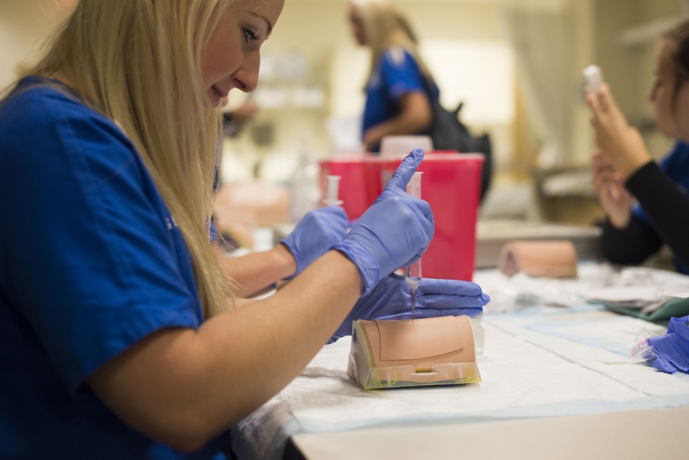 GVL / Luke Holmes - Megan Buchman practices giving a shot to a test dummy in the Center for Health Sciences building downtown.