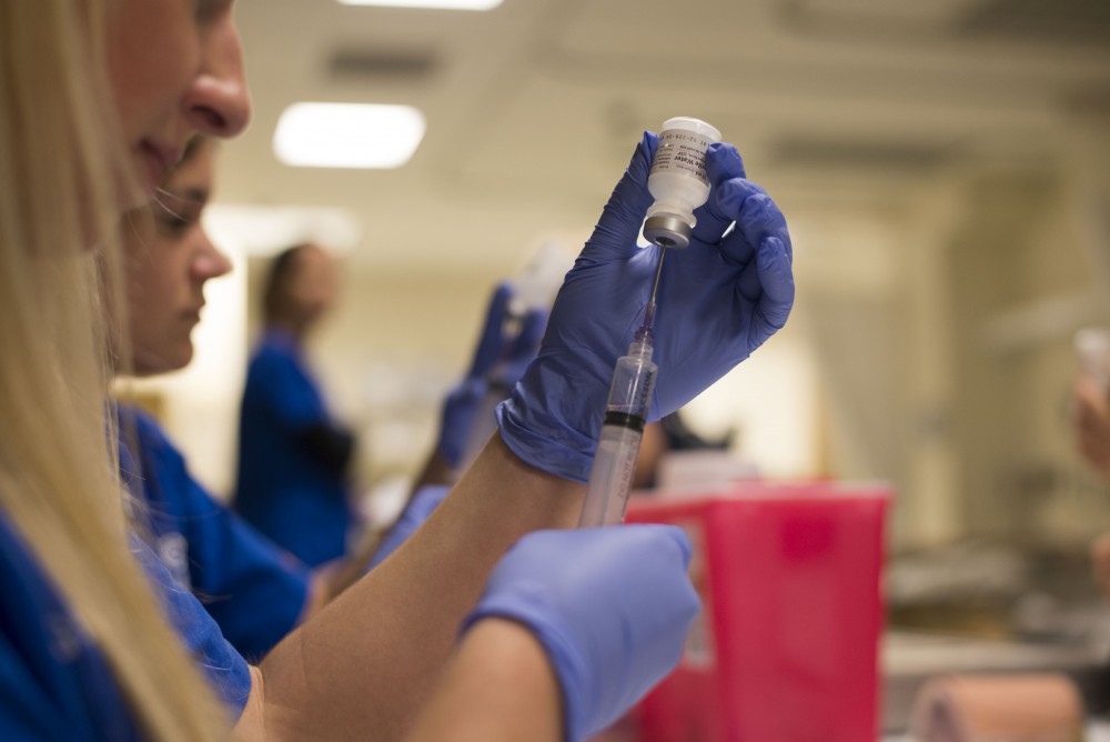 GVL / Luke Holmes - Megan Buchman practices giving a shot to a test dummy in the Center for Health Sciences building downtown.