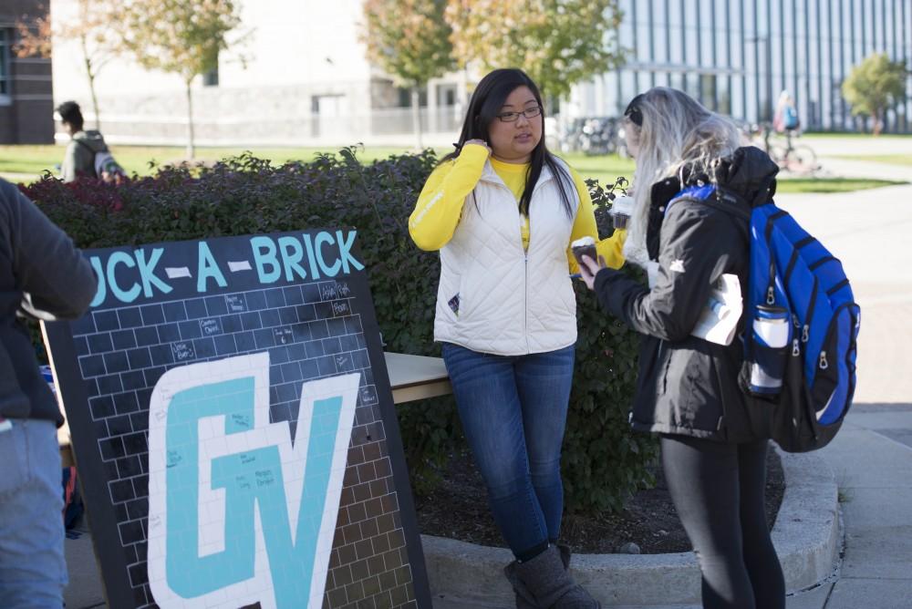 GVL / Luke Holmes - Kaylee Harmon explains the "Buck-A-Brick" board to a student. GVSU Founders Day was celebrated on Tuesday, Oct. 25, 2016 next to the clock tower.