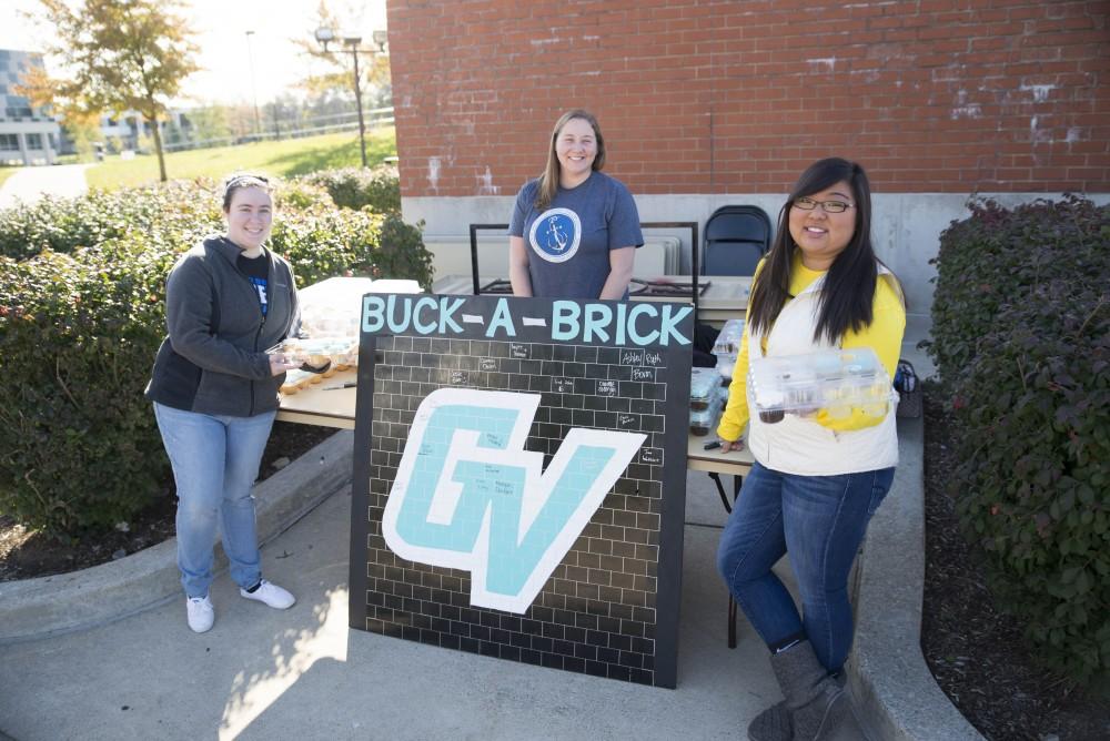 GVL / Luke Holmes - Kimberly Long (left), Megan Ellinger (middle), and Kaylee Harmon (right) help pass out cupcakes on Founders Day. GVSU Founders Day was celebrated on Tuesday, Oct. 25, 2016 next to the clock tower.