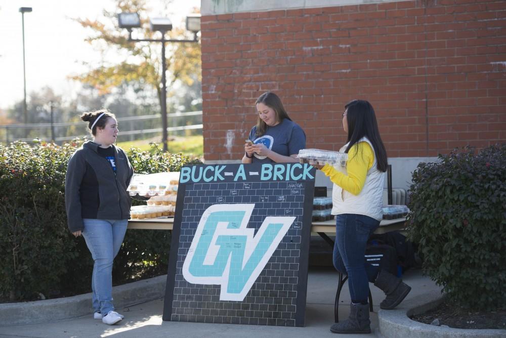 GVL / Luke Holmes - Kimberly Long (left), Megan Ellinger (middle), and Kaylee Harmon (right) help pass out cupcakes on Founders Day. GVSU Founders Day was celebrated on Tuesday, Oct. 25, 2016 next to the clock tower.