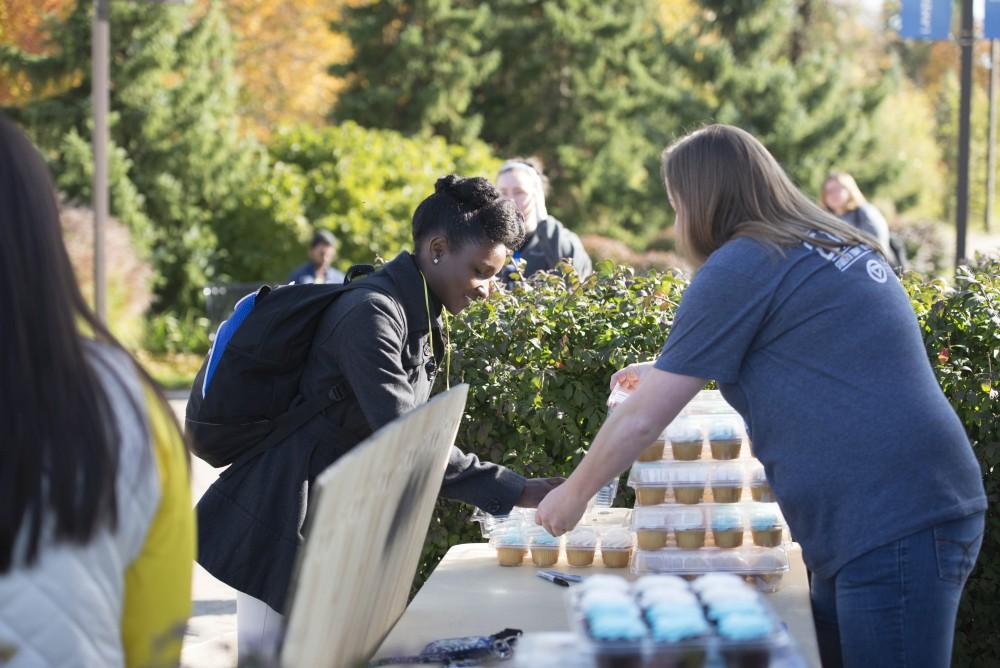 GVL / Luke Holmes - Megan Ellinger passes out a cupcake to a student. GVSU Founders Day was celebrated on Tuesday, Oct. 25, 2016 next to the clock tower.