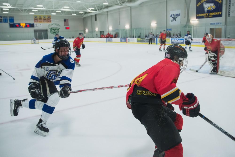 GVL / Luke Holmes - Reede Burnett (12) pokes his stick at the player with possession of the puck. GVSU Men’s D2 Hockey defeated Ferris State University with a score of 8-1 on Saturday, Oct. 16, 2016.