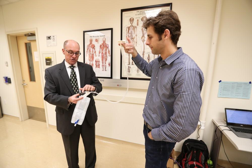 GVL/Kevin Sielaff - Members of the aMDI team Kevin Weaver (right) and Brent Nowak (left) demonstrate an external catheter device that is used to prevent UTI's inside of the Cook-DeVos Center for Health Sciences Wednesday, Oct. 26, 2016.  