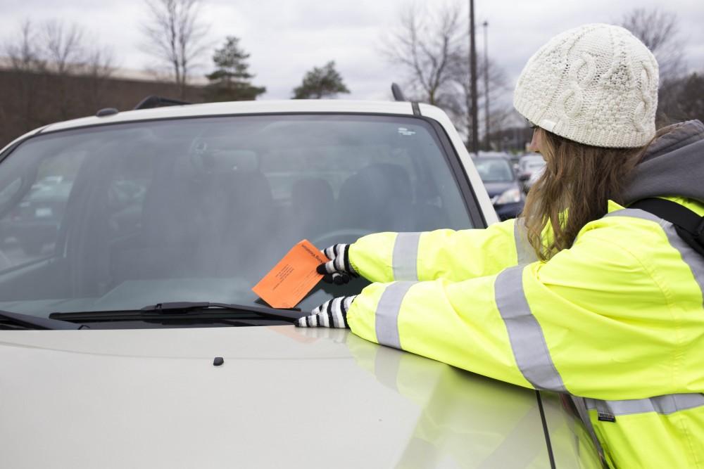 GVL / Sara Carte - Parking attendant Taylor Szost tickets a car on Grand Valleys Allendale campus on Wednesday, Nov. 30, 2016.