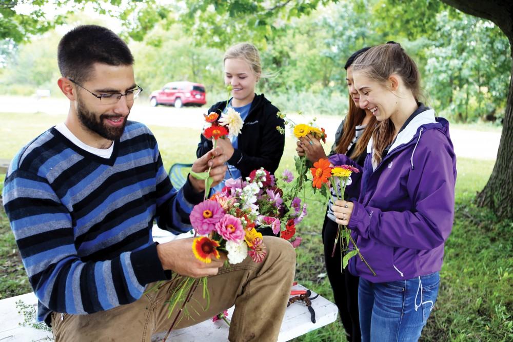 GVL/Emily Frye - Youssef Darwich (left) gathers bouquets of flowers alongside several Grand Valley student volunteers at the GVSU Sustainability Farm on Friday Sept. 30, 2016. Darwich will be the first to present at “Climate Change—It’s in Our Hands: How Food Choices Impact the Earth” which will be held Tuesday, Jan. 24, at the L.V. Eberhard Center from 7 p.m. to 9 p.m.