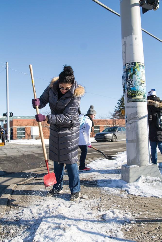 GVL/Sara Carte - Grand Valley Public and Non-Profit Administration student, Reshonda Williams, shovels the sidewalks along Grandville Avenue downtown Grand Rapids for the Martin Luther King community service projects on Friday, Jan. 22, 2016.