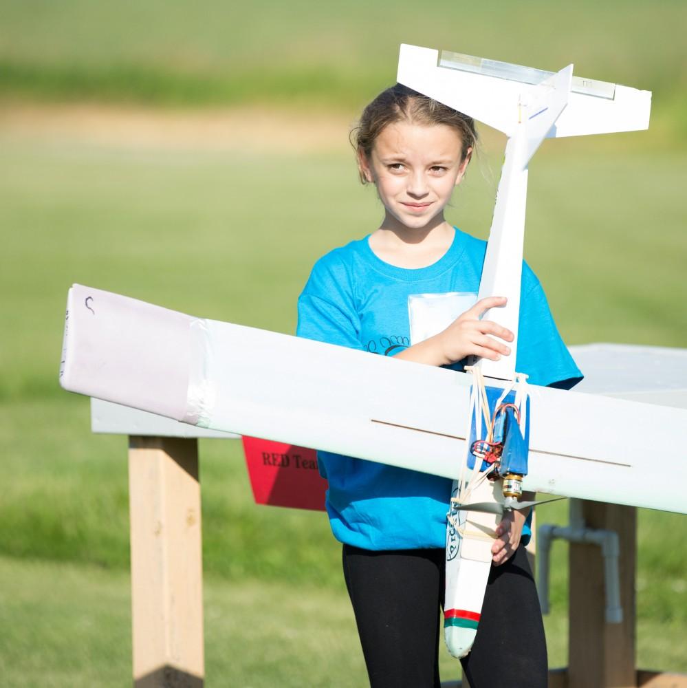 GVL / Kevin Sielaff - Stephanie Wrogg holds up her airplane after it has landed. Students of STEPS (Science, Technology, and Engineering Day Camps) fly planes that they have built during camp at Warped Wings Fly Field in Allendale on Thursday, June 23, 2016. 