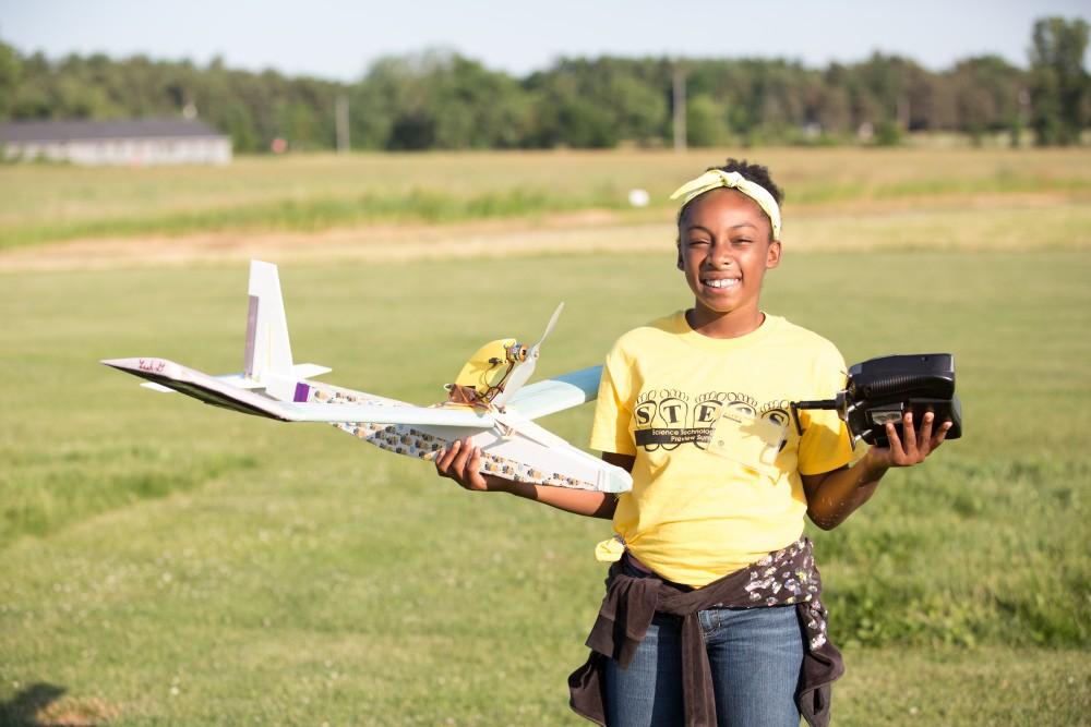 GVL / Kevin Sielaff - Leah Garyson poses for a photo with her plane at Warped Wings Field. Students of STEPS (Science, Technology, and Engineering Day Camps) fly planes that they have built during camp at Warped Wings Fly Field in Allendale on Thursday, June 23, 2016. 