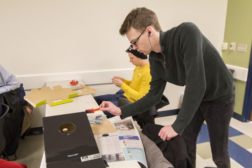 GVL/Mackenzie Bush - Parker Ykimoff prepares his board game for the upcoming GVSU WInter Cardboard Challenge Friday, Feb. 17, 2017 in Mackinaw Hall.