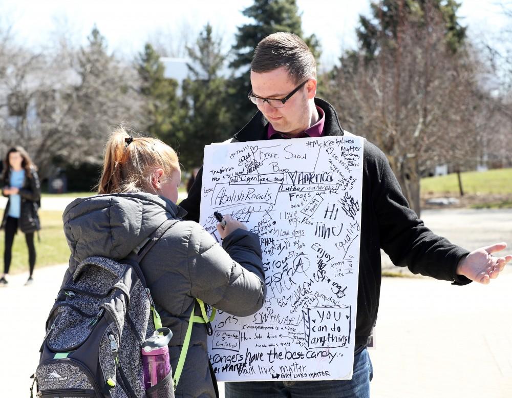 GVL/Kevin Sielaff - A Grand Valley student writes on Nathan Williamson's free speech board on Wednesday, Mar. 22, 2017 outside of Zumberge Hall on Grand Valley's Allendale campus. 