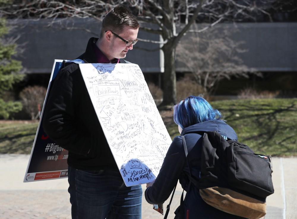 GVL/Kevin Sielaff - Riley Collins writes on Nathan Williamson's free speech board on Wednesday, Mar. 22, 2017 outside of Zumberge Hall on Grand Valley's Allendale campus. 