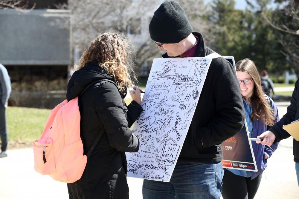 GVL/Kevin Sielaff - Lauren Clark writes on Nathan Williamson's free speech board on Wednesday, Mar. 22, 2017 outside of Zumberge Hall on Grand Valley's Allendale campus. 