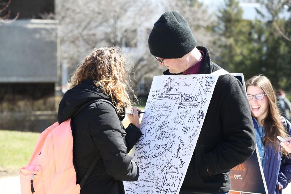 GVL/Kevin Sielaff - Lauren Clark writes on Nathan Williamson's free speech board on Wednesday, Mar. 22, 2017 outside of Zumberge Hall on Grand Valley's Allendale campus. 