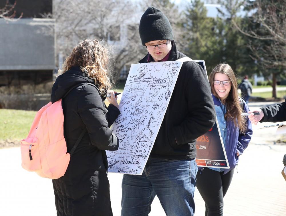 GVL/Kevin Sielaff - Lauren Clark writes on Nathan Williamson's free speech board on Wednesday, Mar. 22, 2017 outside of Zumberge Hall on Grand Valley's Allendale campus. 