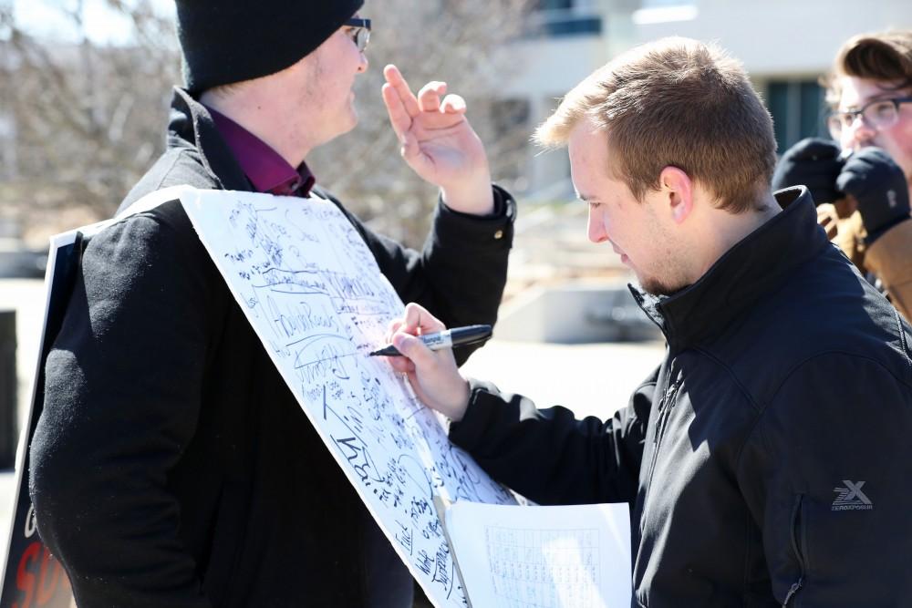 GVL/Kevin Sielaff - Tim McKeeby writes on Nathan Williamson's free speech board on Wednesday, Mar. 22, 2017 outside of Zumberge Hall on Grand Valley's Allendale campus. 