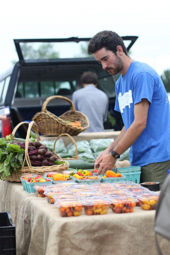 GVL / Luke Holmes - Austin VanDyke sets out some fresh peppers at the Farmers Market in Parking Lot G on Wednesday, Sept. 7, 2016.
