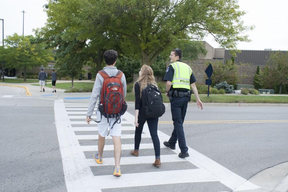 GVL / Emily Frye 
Officer Andrew Hintz assists GVSU students, Robbie Triano and Becky Oppman, across the street on Wednesday September 13, 2017.