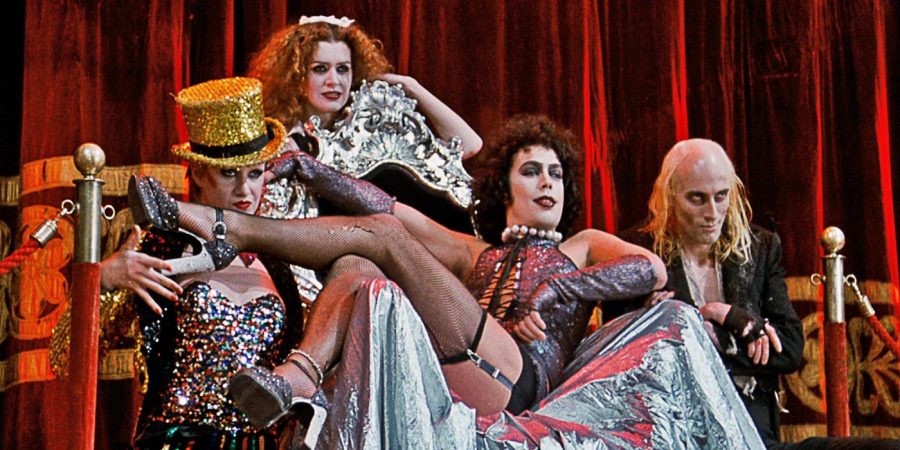 Tim Curry, Patricia Quinn, Richard O'Brien, and Nell Campbell in The Rocky Horror Picture show, seated in and around a garish throne