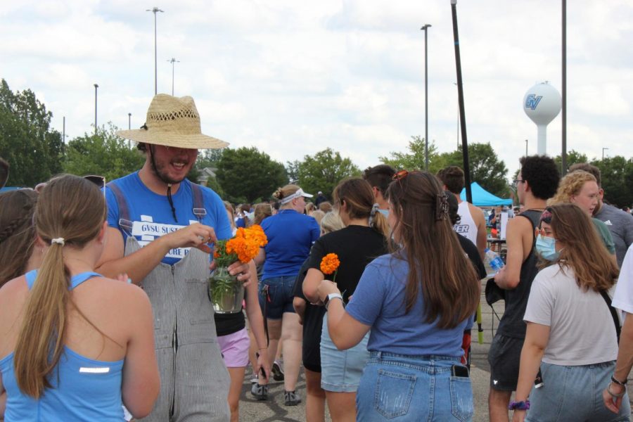 Member from GVSU's Sustainable Agriculture Project handing out flowers to attendees at Campus Life Night